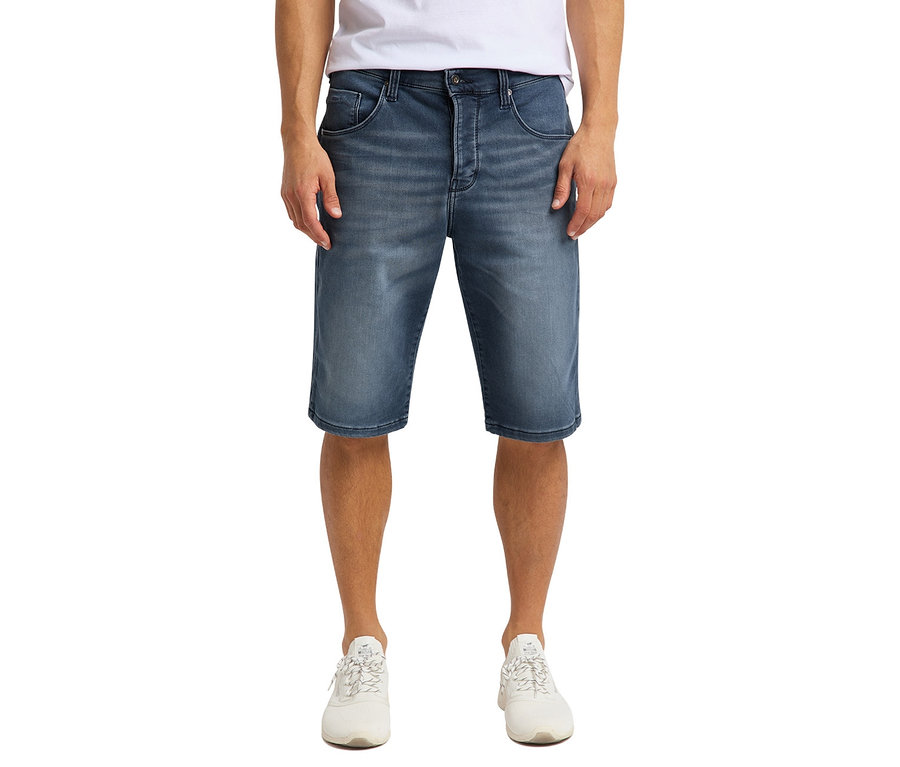Mann posiert in Denim-Bermuda-Shorts »Mustang« und weißen Turnschuhen.