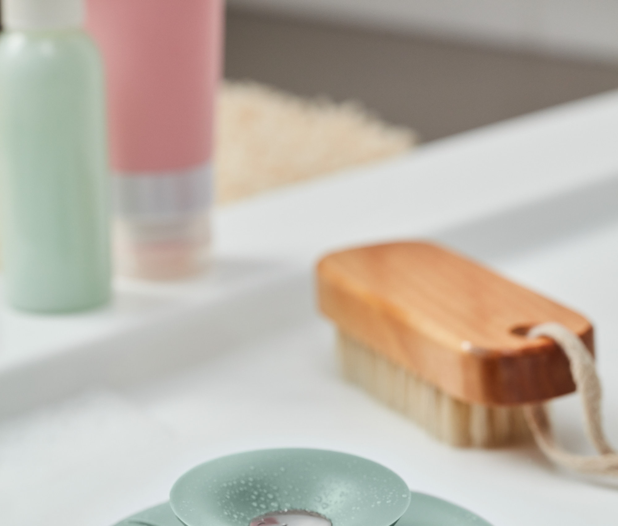 Ein grünes Abflusssieb und -verschluss liegt im Waschbecken.