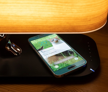 Handy liegt auf Induktiv-Ladestation mit BT-Lautsprecher und Lampe.