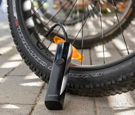 Eine schwarze elektrische Pumpe "VoltPump" lehnt an einem Fahrradreifen.
