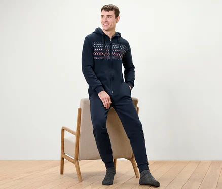 Mann sitzt auf Stuhl, trägt blauen Lounge-Overall.