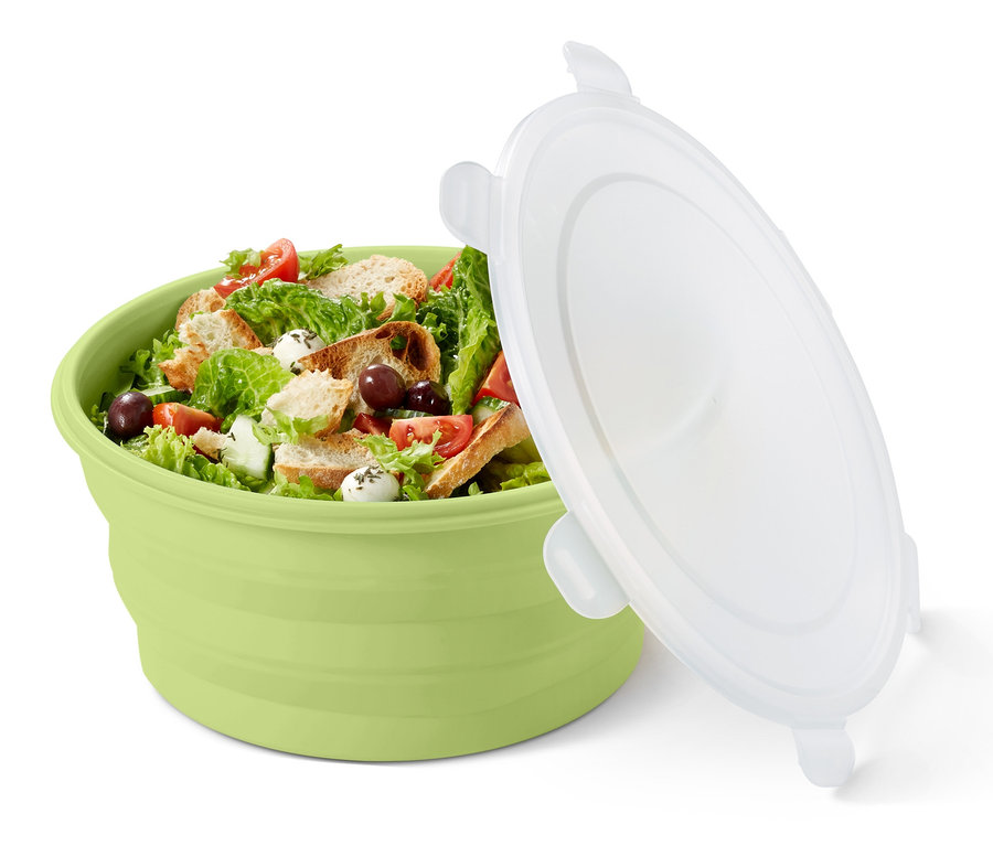Eine grüne, faltbare Salatschüssel gefüllt mit Salat und ein weißer Deckel daneben.