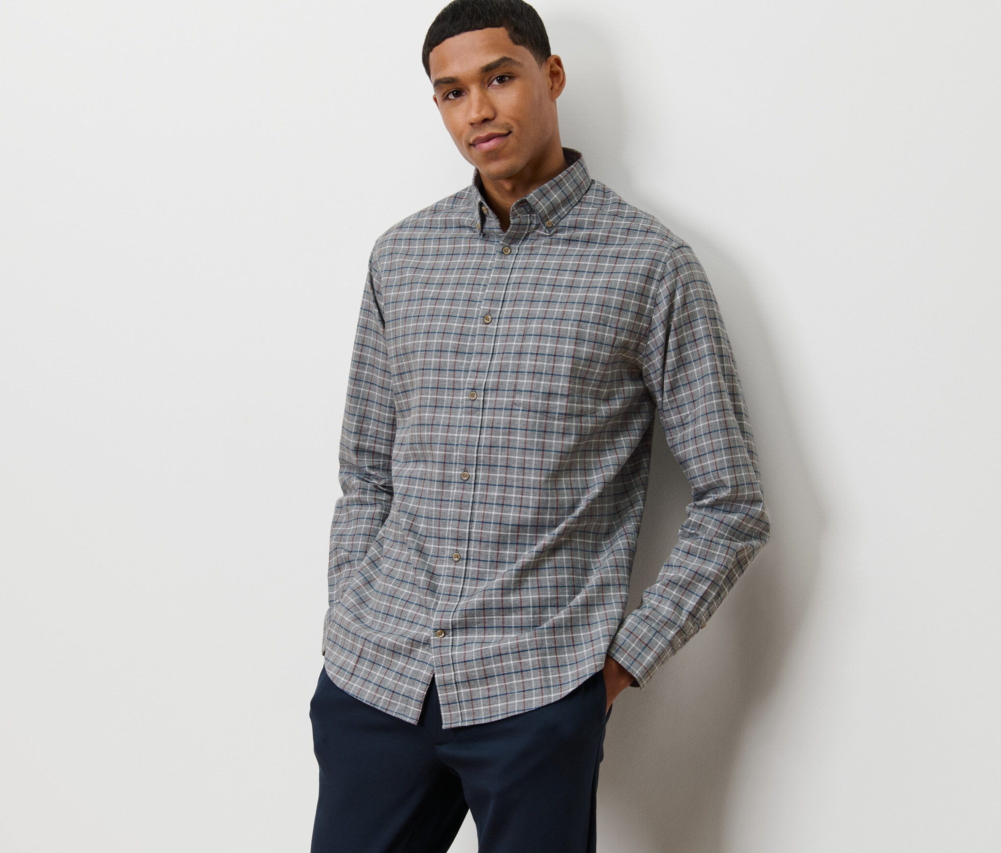 Mann posiert in grauem Flanell-Hemd.