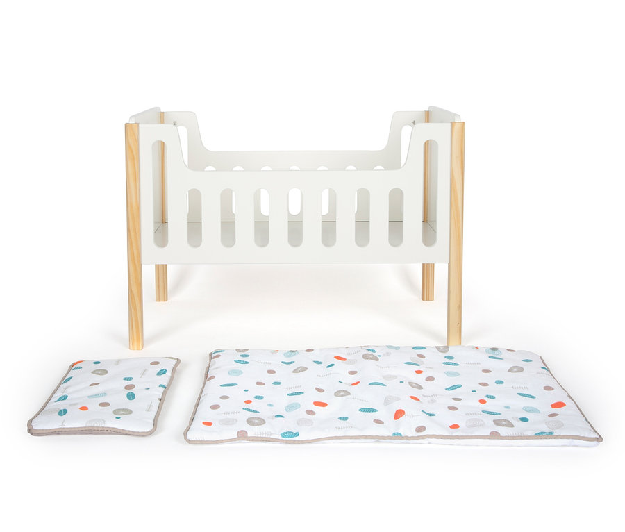 Ein small foot Puppengitterbett »Little Button« und eine bedruckte Unterlage mit Kissen auf weißem Hintergrund.