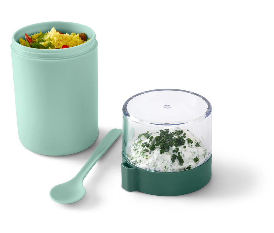 Türkisbehälter mit Essen, Salat und Löffel neben einem Glas mit Dip.