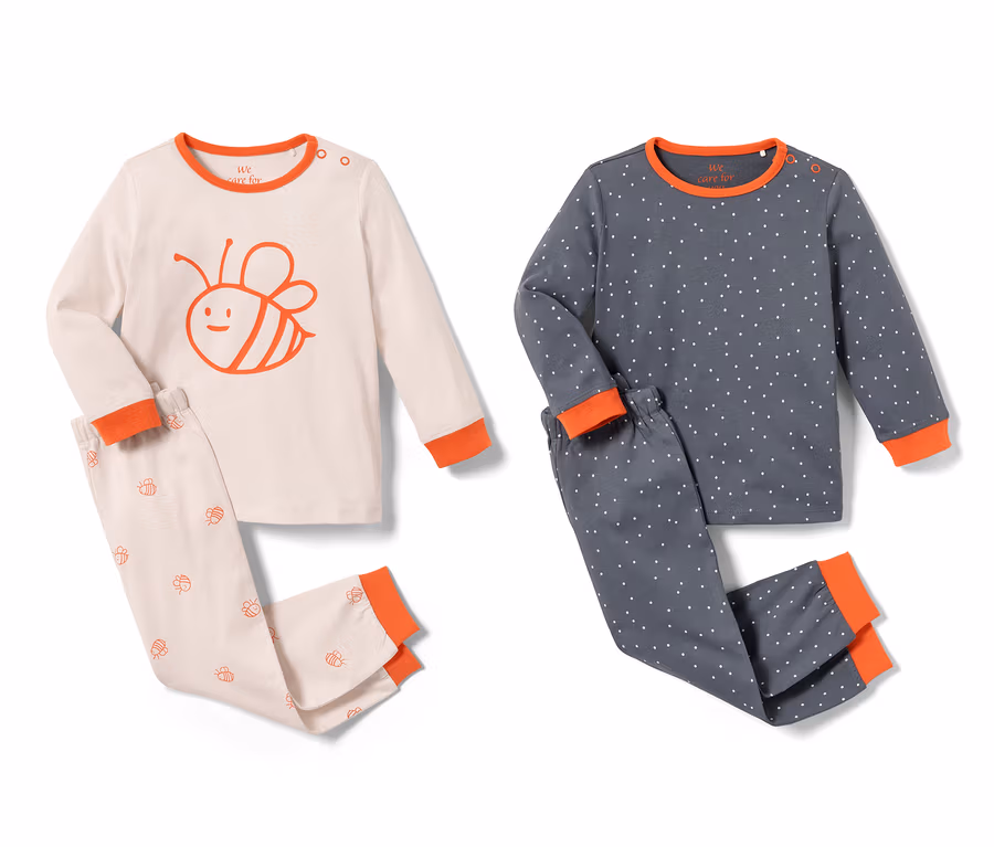 Zwei Kleinkinder-Pyjamas, ein rosa Pyjama mit Bienenmuster und ein blauer mit weißen Punkten.