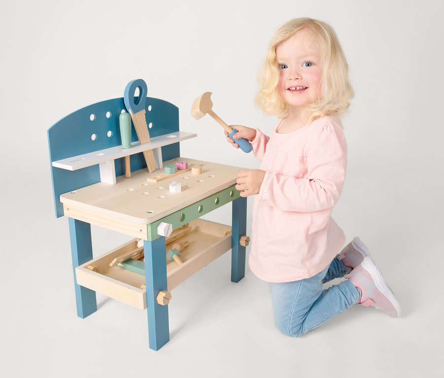 Mädchen kniet an small foot Werkbank kompakt »Nordic« und hält Hammer.