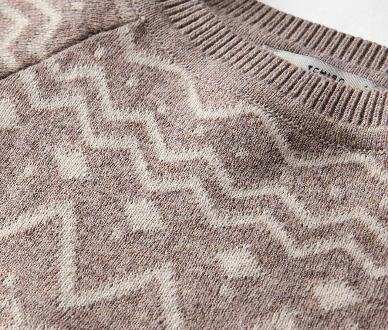 Detailaufnahme eines braunen Pullovers mit Muster.