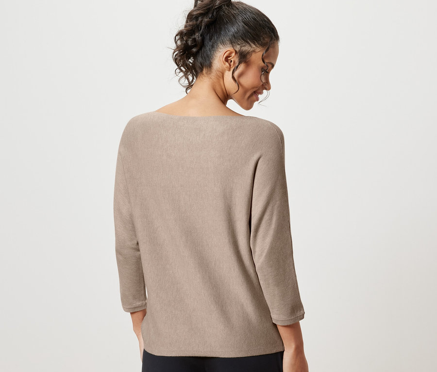 Rückansicht einer Frau mit hochgesteckten Haaren, die einen beige melierten Feinstrickpullover trägt.