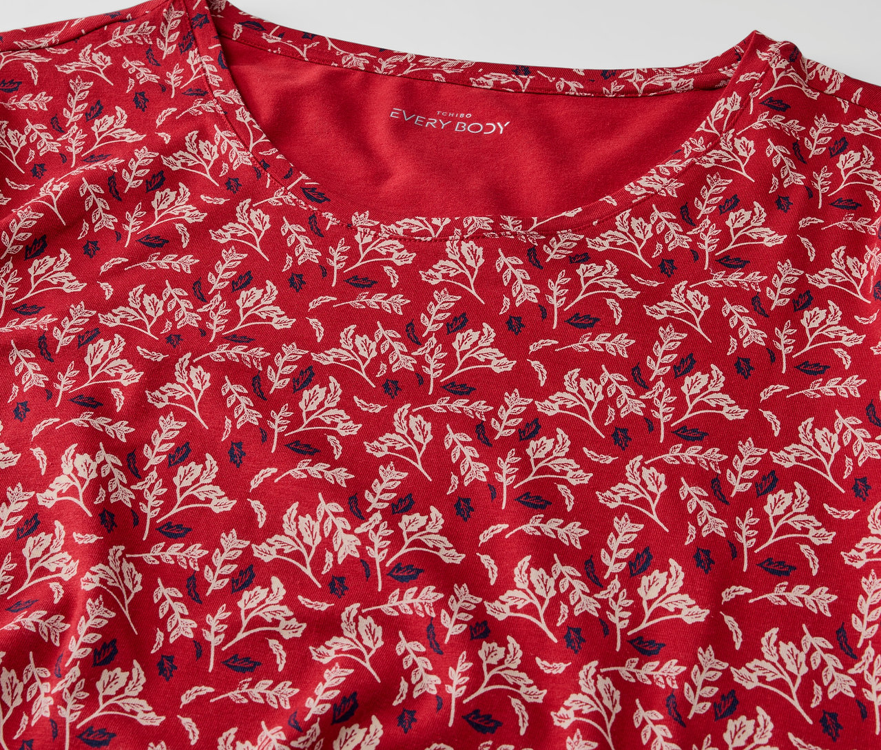 Detailansicht eines roten T-Shirts mit Blattmuster.