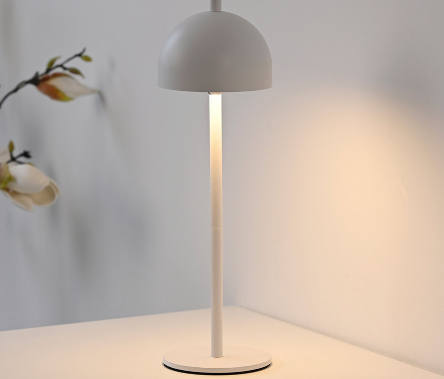 Eine weiße Lampe steht auf einem weißen Tisch.