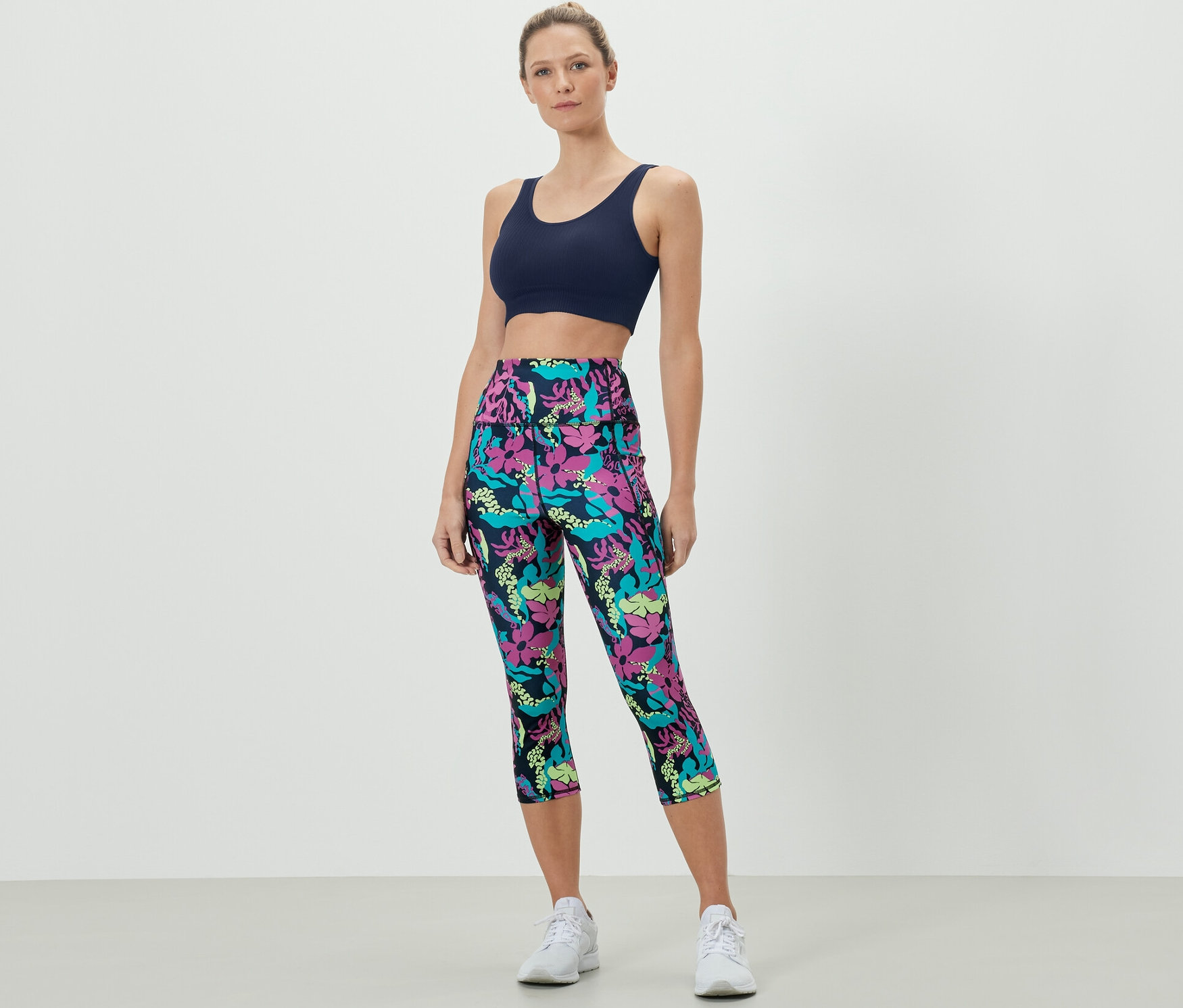 Frau trägt einen Sport-BH und eine 3/4 Sporttight mit Alloverprint.