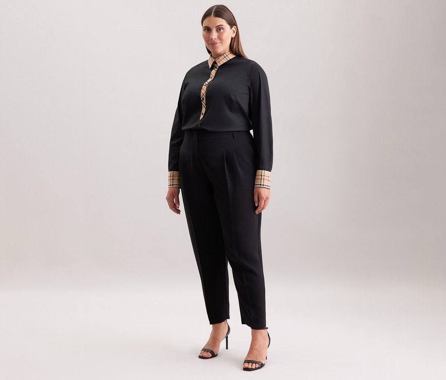 Frau trägt eine schwarze Hose und eine Seidensticker Popeline-Bluse mit Karodetail und schwarze High Heels.