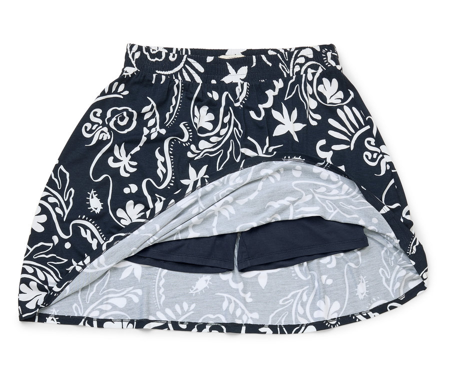 Ein marineblauer Rock mit weißem Blumenmuster und integrierten Shorts liegt auf einem weißen Hintergrund.