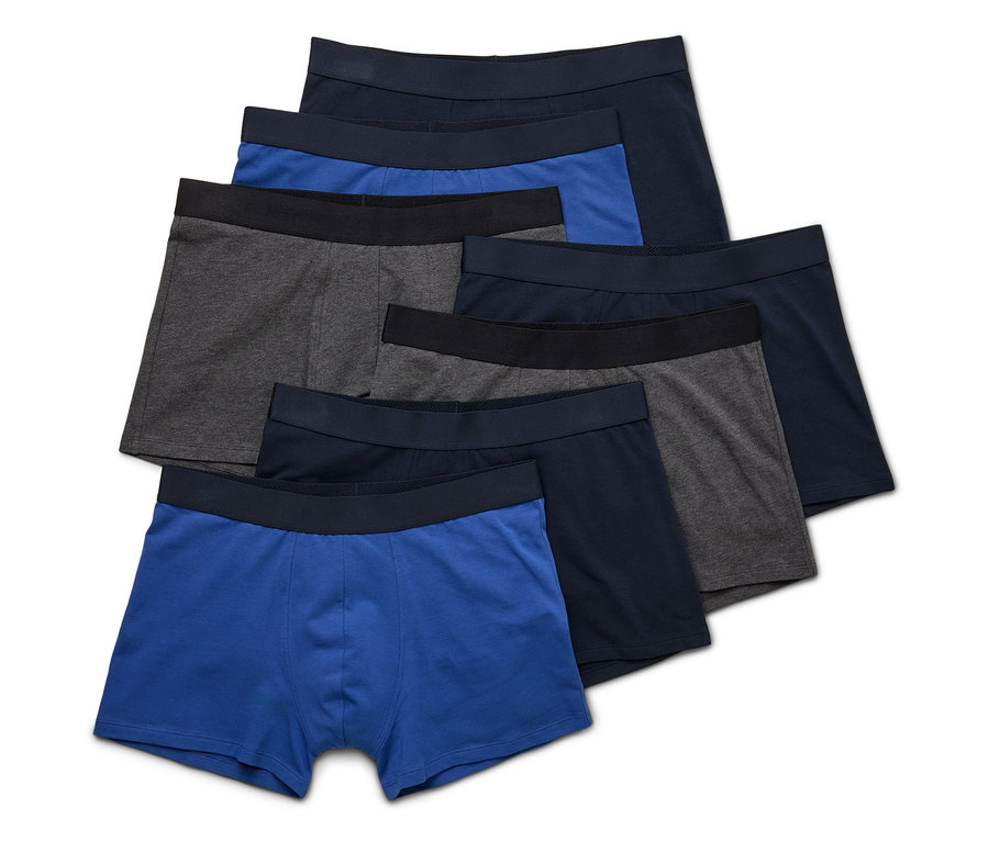 Mehrere Boxershorts in Blau-, Grau- und Schwarztönen liegen übereinander.