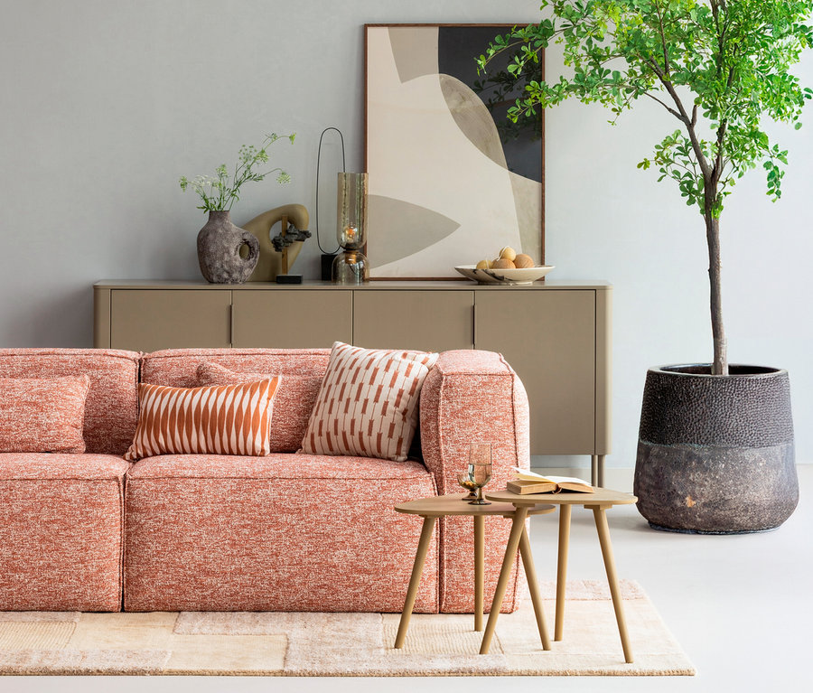 Wohnzimmer mit orangefarbenem Sofa mit Kissen auf einem sandfarbenen WOOOD Handgewobener Teppich »Noven«, 170 x 240 cm.
