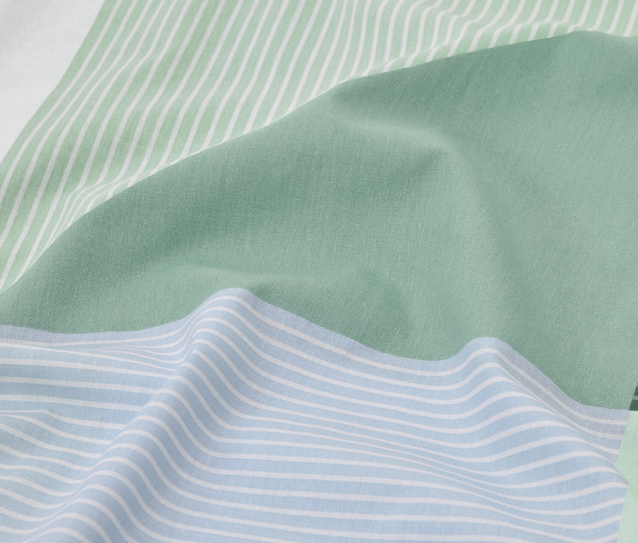 Nahaufnahme von hellblauer und grüner Bettwäsche mit Streifen.