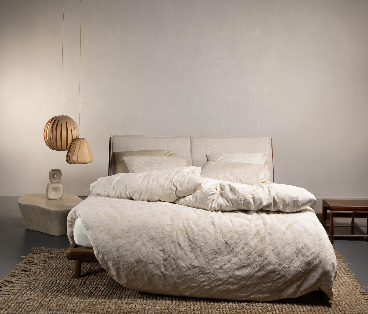 Schlafzimmer mit einem Bett mit Essenza Bettwäsche »Maribel« in Normalgröße und Übergröße, Nachttisch und Lampe.