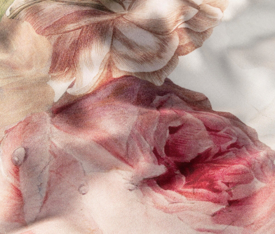 Nahaufnahme von rosa Rosenblüten auf einem Stoff mit Blümchenmuster.