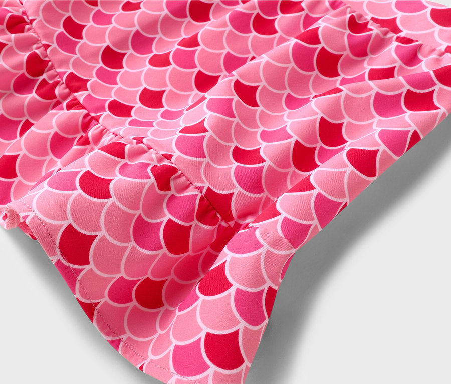 Nahaufnahme eines pinkfarbenen Stoffes mit Fischschuppenmuster.