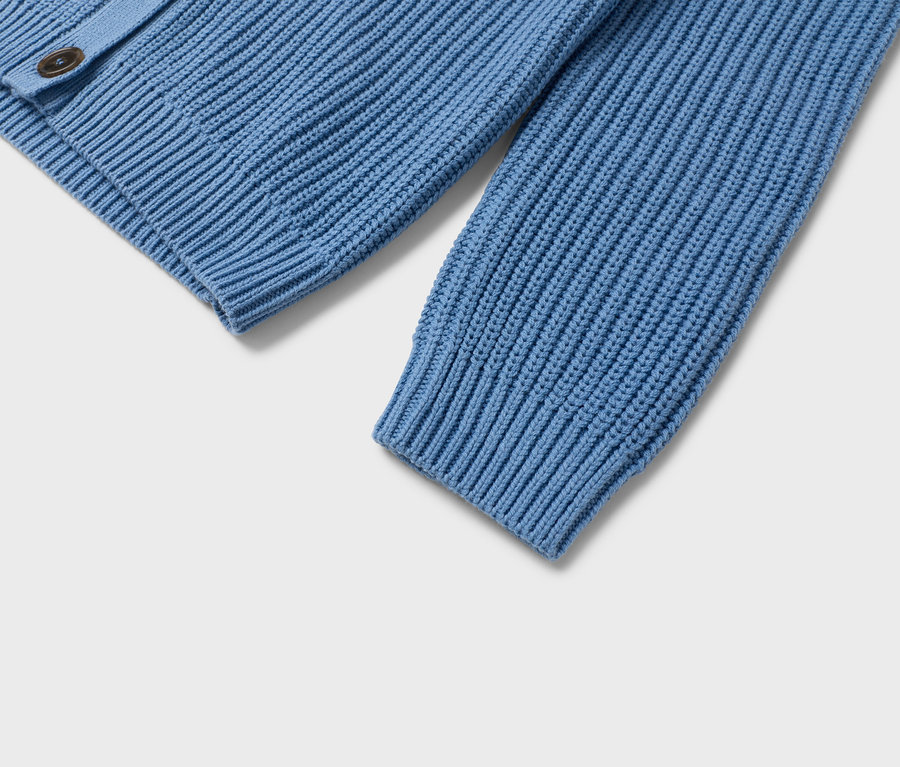 Detailansicht einer hellblauen Strickjacke mit braunen Knöpfen.