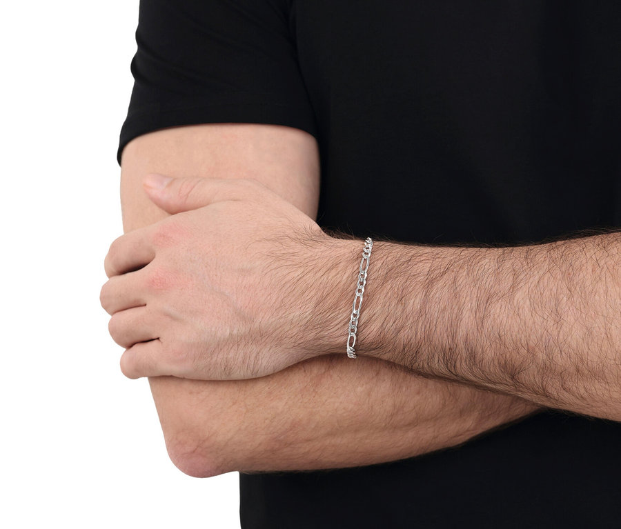 Mann trägt ein silbernes Armband am Handgelenk, vor schwarzem Hintergrund.