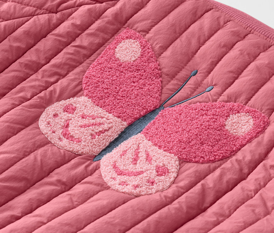Detailaufnahme einer gesteppten, rosafarbenen Jacke mit rosafarbenem Schmetterlingsaufnäher.