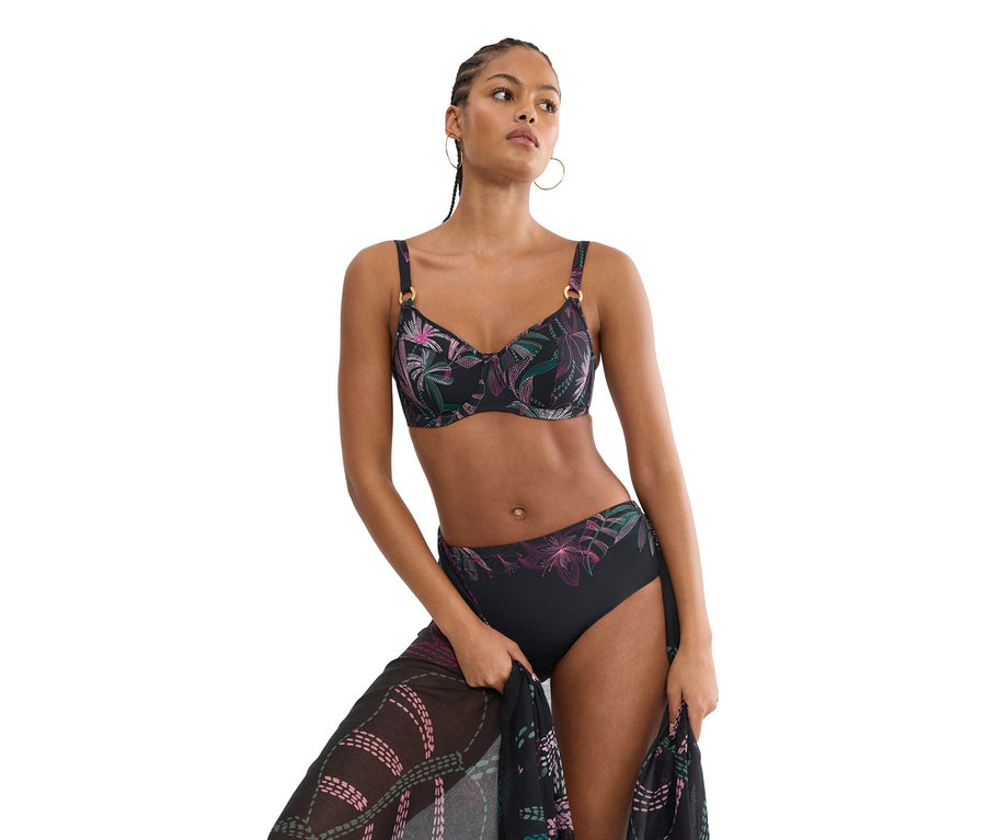 Frau trägt einen schwarzen Bikini mit Blumenmuster und hält einen passenden Pareo.