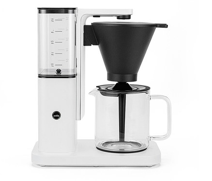 Weiße Wilfa Kaffeemaschine mit Wasserbehälter, schwarzem Filter und Glaskanne auf weißem Untergrund.