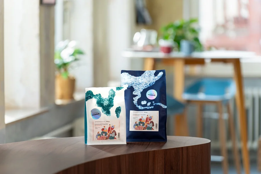 Zwei Kaffeepackungen stehen auf einem Tisch, eine weiße und eine blaue.