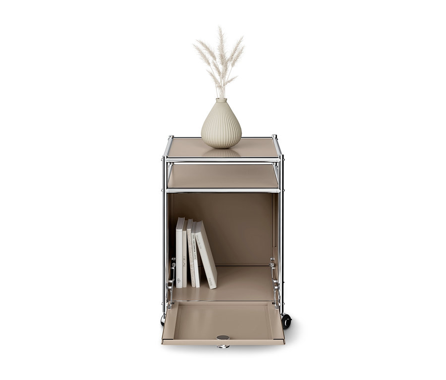 Beiges modulares Rollregal mit Chromrahmen, auf dem eine Vase mit Trockengras steht. Das untere Fach ist geöffnet und enthält Bücher.