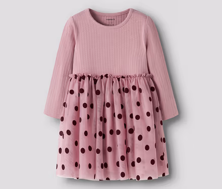 Rosa Langarmkleid mit geripptem Oberteil und einem durchsichtigen Rock mit dunklen Tupfen. Die Taille ist gerafft.