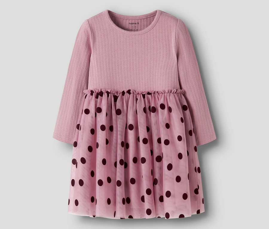 Rosa Langarmkleid mit geripptem Oberteil und einem durchsichtigen Rock mit dunklen Tupfen. Die Taille ist gerafft.