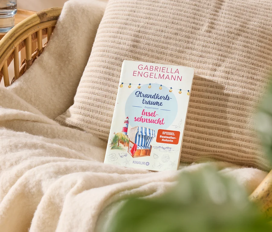 Auf einem Sessel liegt ein Buch mit dem Titel "Strandkorbträume Inselsehnsucht" von Gabriella Engelmann.