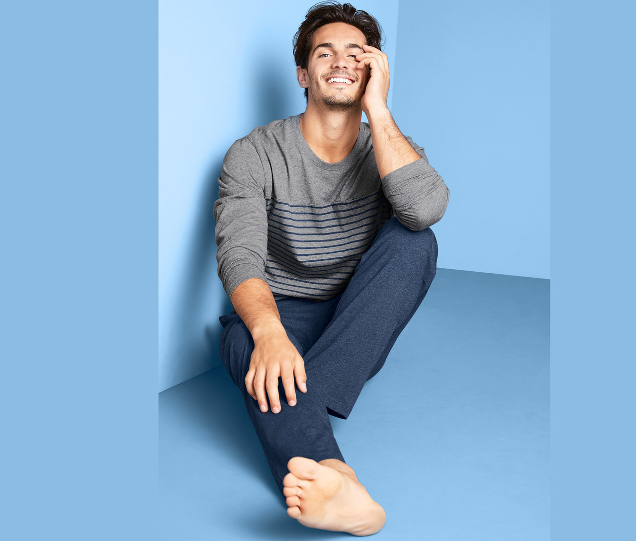 Mann sitzt auf dem Boden und trägt einen Pyjama.