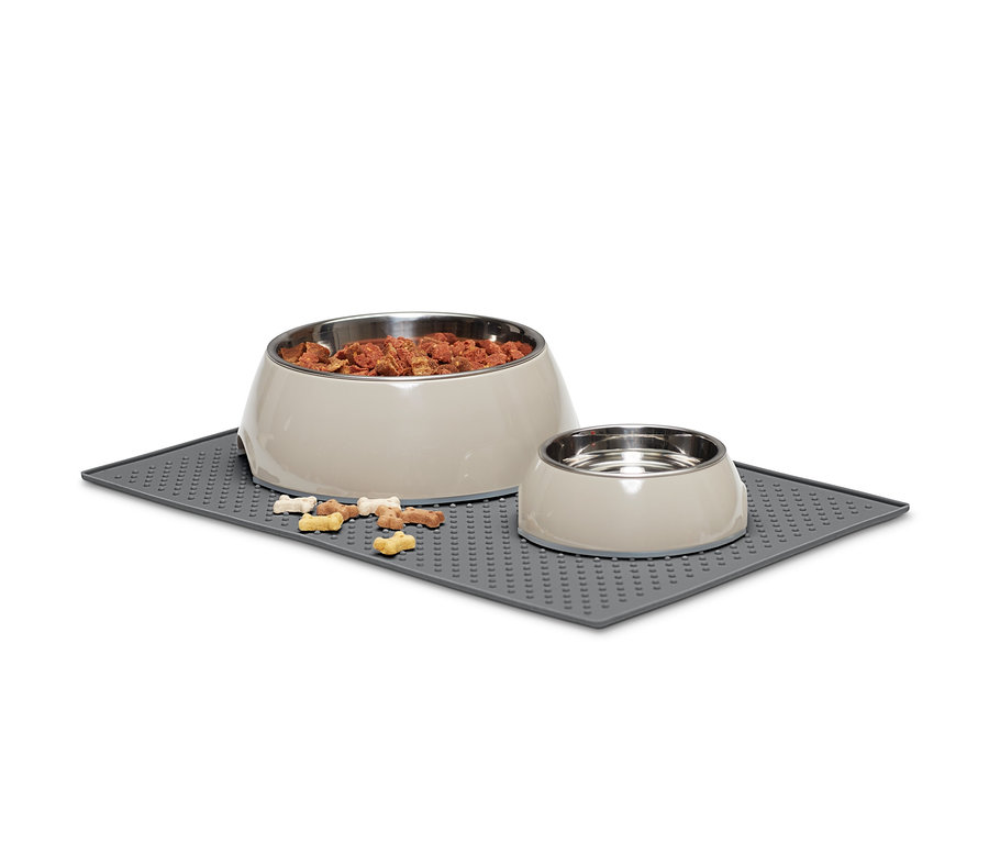 Zwei Futternäpfe stehen auf einem Futternapfuntersetzer, um die herum Futterstücke verstreut sind.