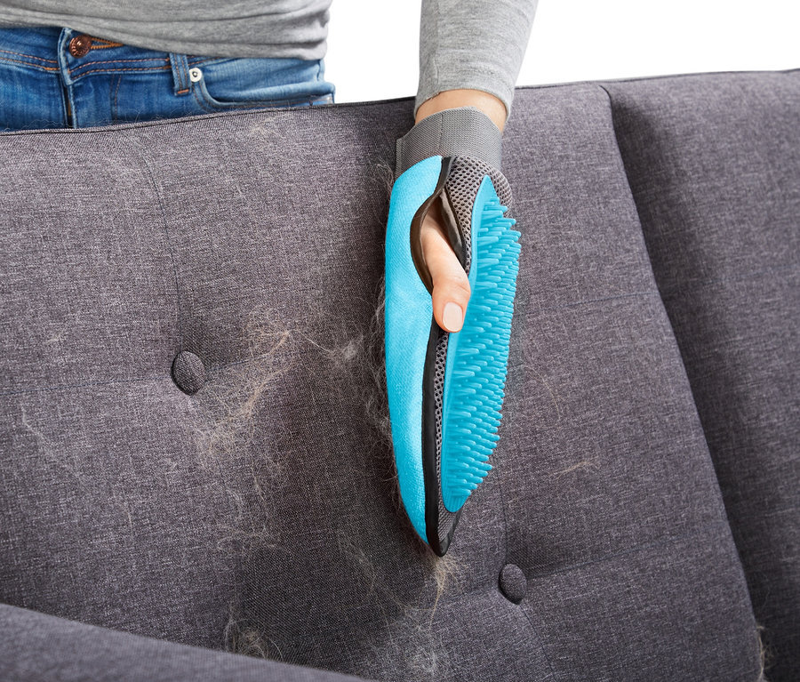 Frau entfernt Haare von Sofa mit Fellpflege-Handschuh.