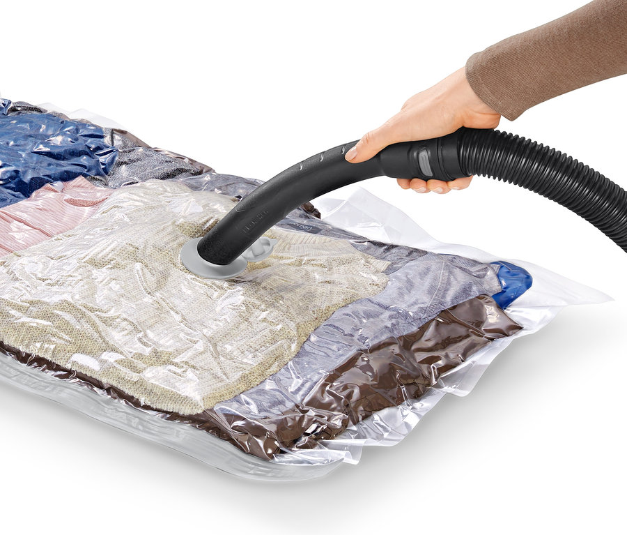 Eine Hand hält einen Staubsaugerschlauch über einem Vakuum-Aufbewahrungsbeutel.