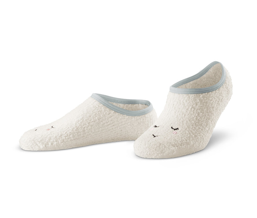 Zwei Paar weiße Hausschuhsocken mit aufgenähtem Gesicht.