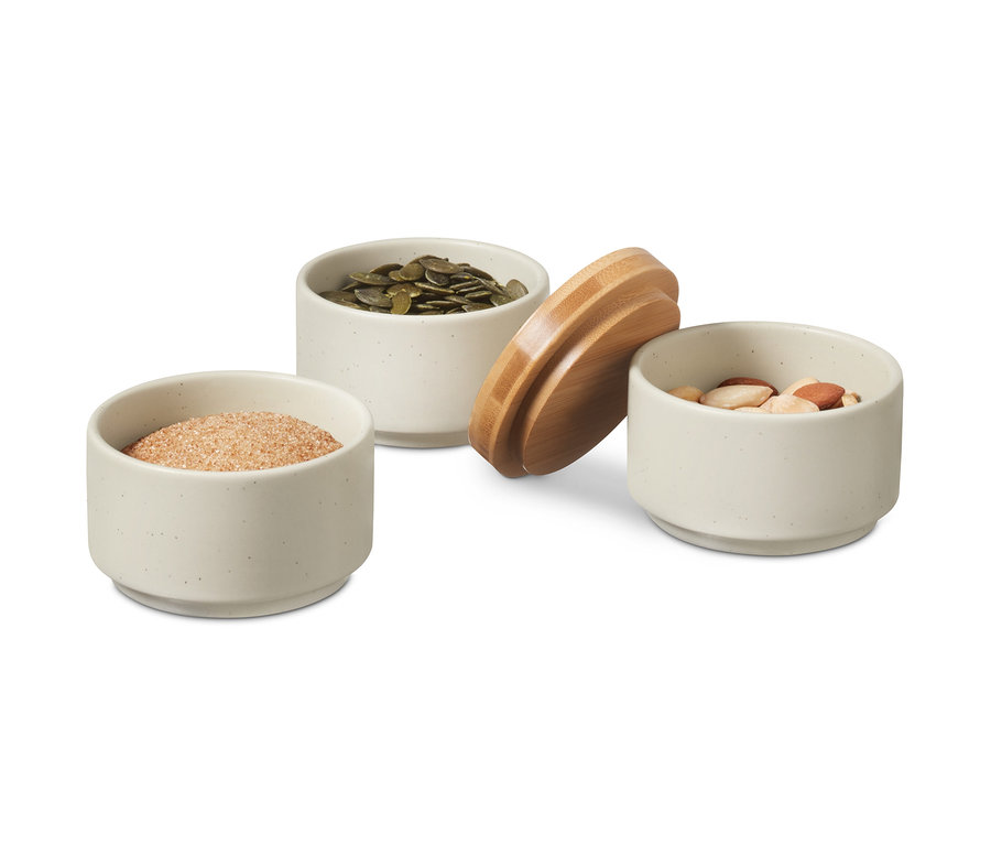 Drei kleine Gewürzdosen, eine mit Zucker, eine mit Kürbiskernen und eine mit Nüssen.