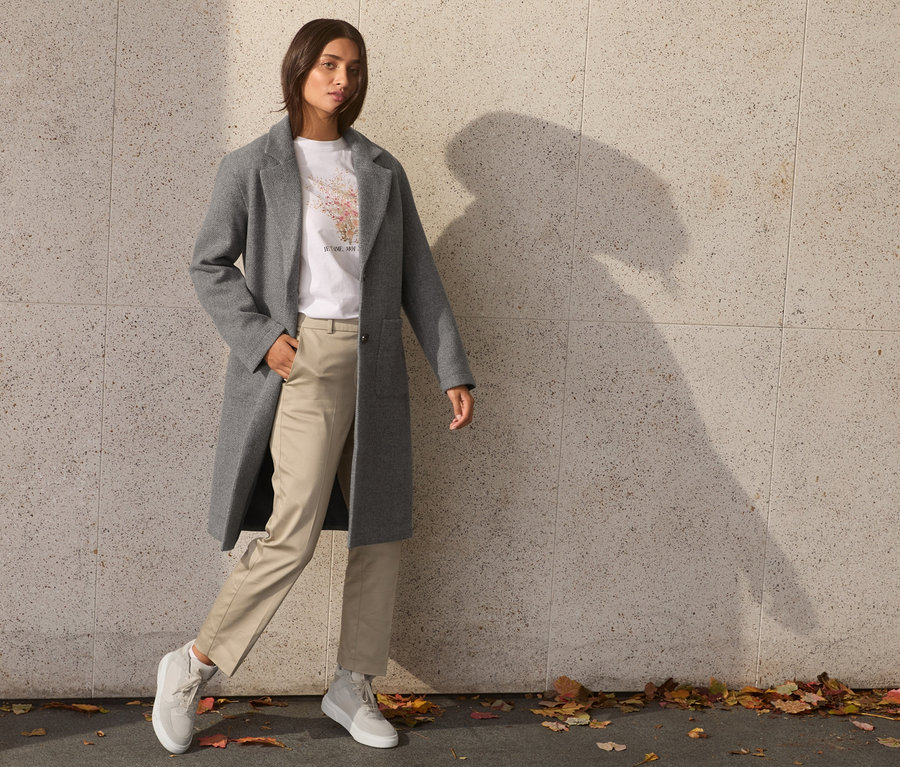 Frau posiert in grauem Mantel.