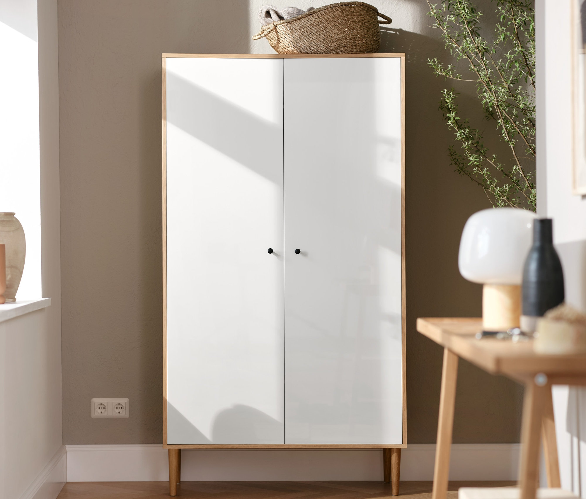 Weißer Schrank steht neben Konsolentisch mit 2 Ablagen. Auf dem Tisch steht eine LED-Akku-Tischleuchte.