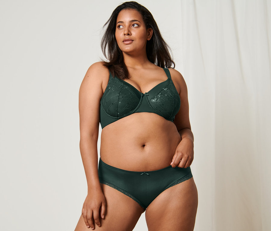 Frau posiert in Minimizer-BH und 2 dunkelgrünen Pantys.