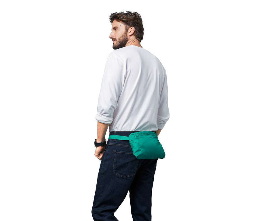 Mann blickt nach links, um seine Taille ist ein grüner Unisex-Regenponcho befestigt.