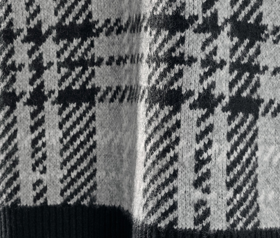 Detailaufnahme eines Strickpullovers mit Hahnentrittmuster.