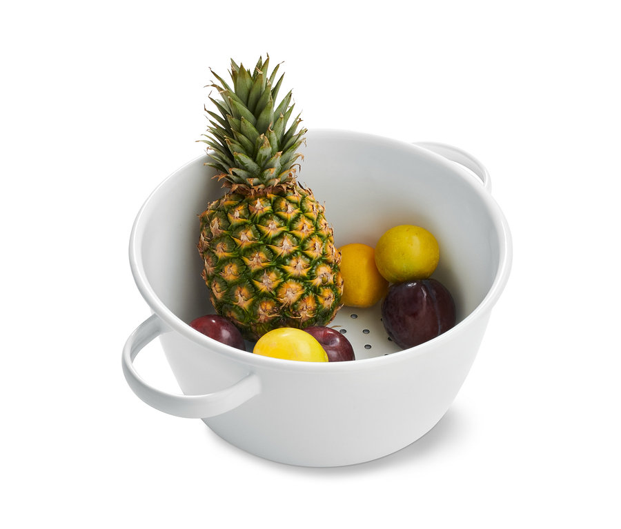 Ananas, Pflaumen und Zitronen in einem Emaille-Sieb.