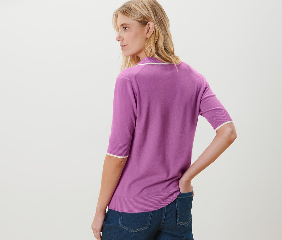 Frau posiert in Jeans und Feinstrick-Polo in Lila.