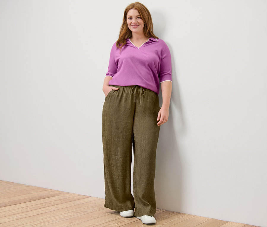 Frau posiert in Feinstrick-Polo und Schlupfhose.