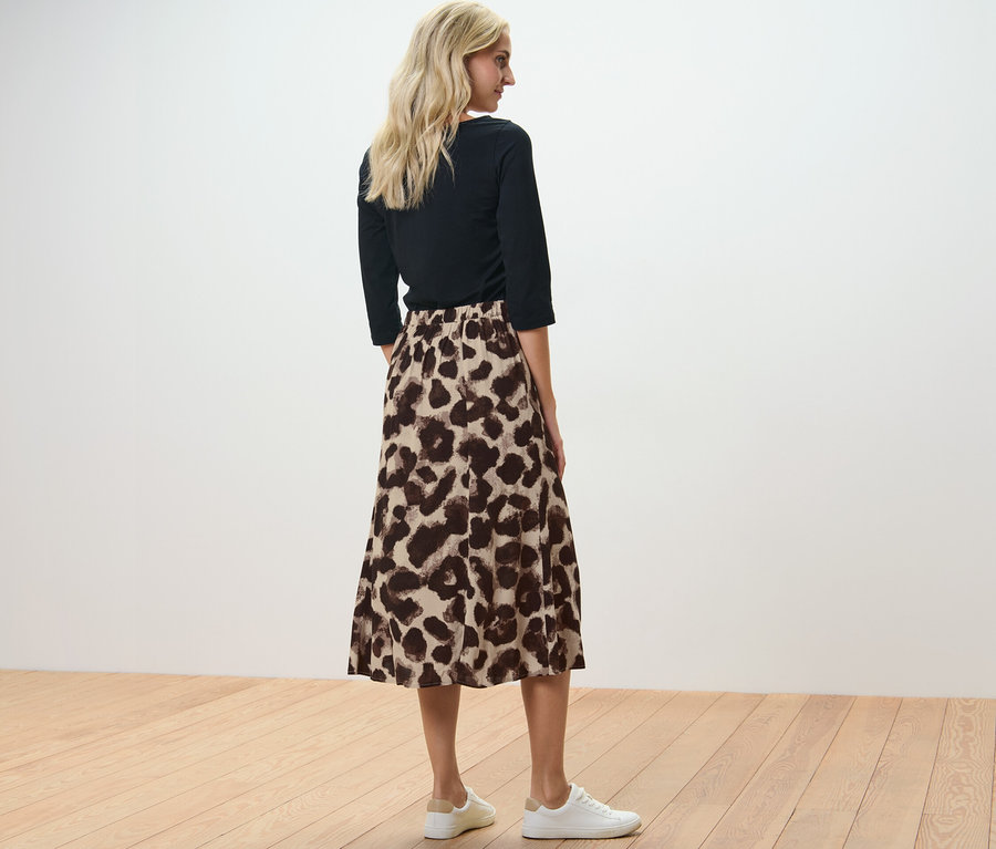 Frau steht mit dem Rücken zur Kamera und trägt einen bedruckten Midirock.