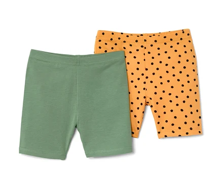 Zwei Kinder-Radler-Leggings: eine grün, die andere orange mit schwarzen Punkten.